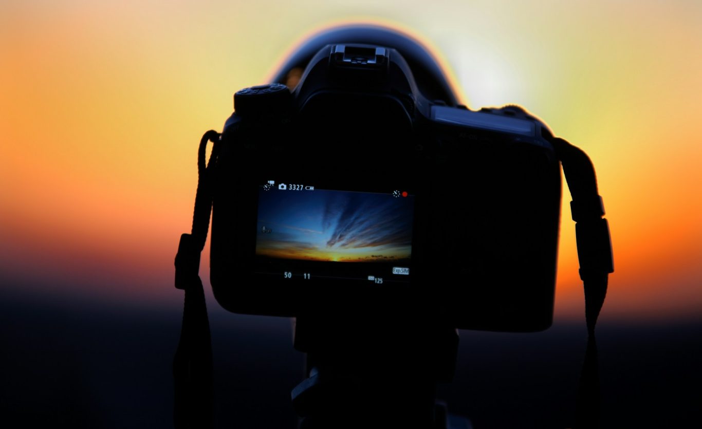Camera capturing a sunset with vibrant colours in the background.