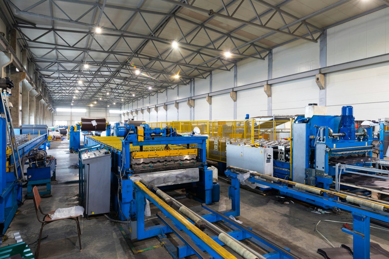 Interior of a large manufacturing facility with blue machinery and workstations.