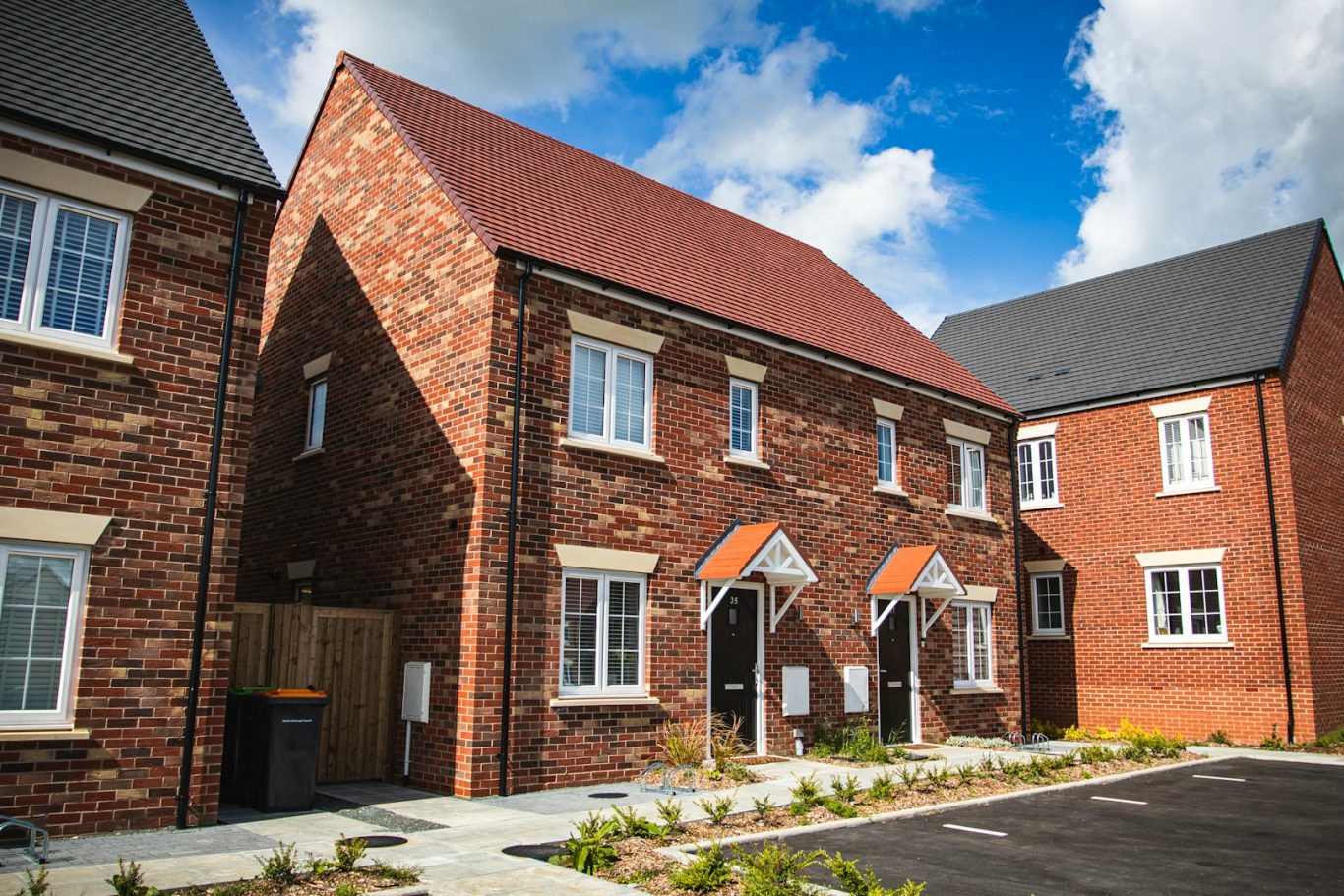 New red-brick residential buildings with pitched roofs and landscaped gardens.